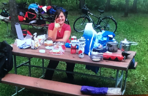 Anabelle Guay dégustant son repas assise à une table à pique-nique lors d'une aventure cycliste, en été.
